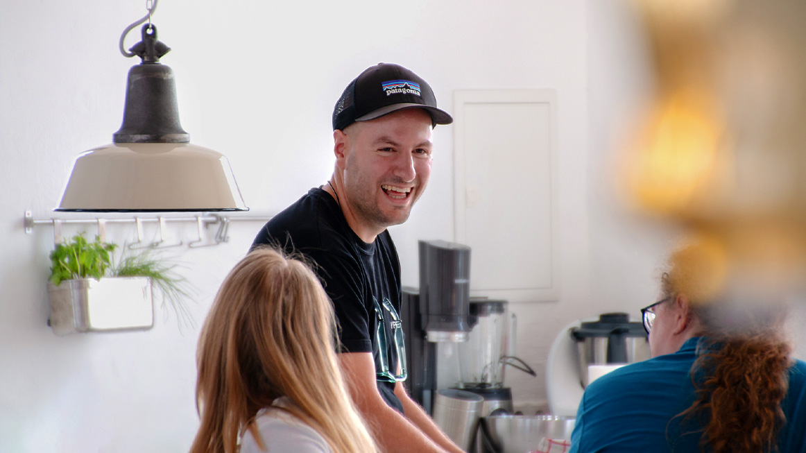 three people in a kitchen scene laughing at a shared story (Photo)