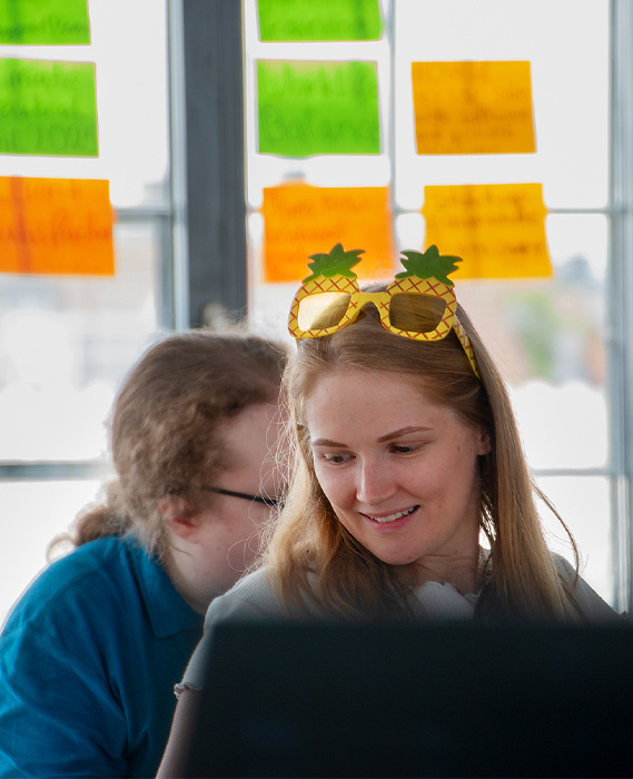 person with pineapple glasses at our yearly stratefy meeting infront of a post-it wall (Photo)