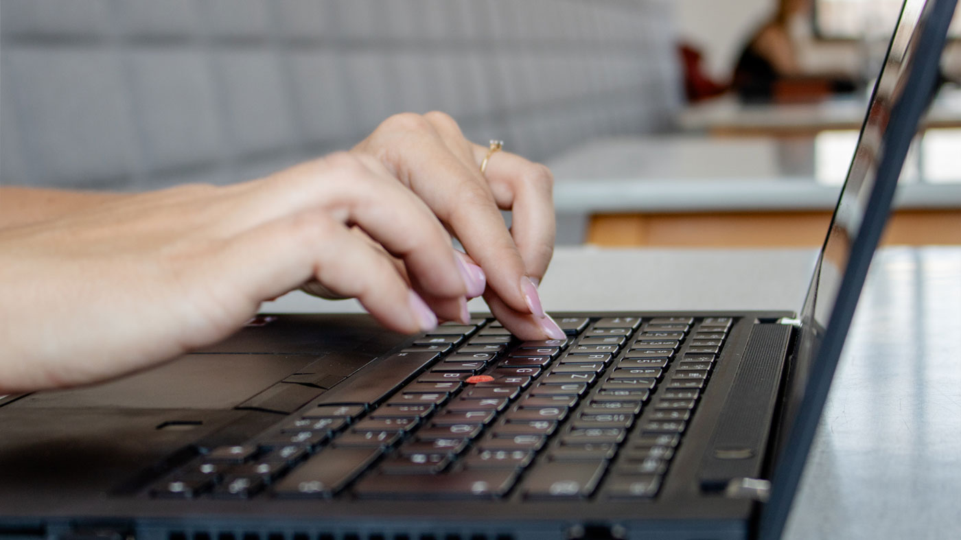 closup of hands with pink nails on a laptop keyboard (Photo)